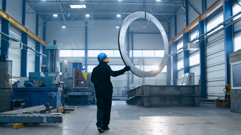 man inspects steel circle in factory