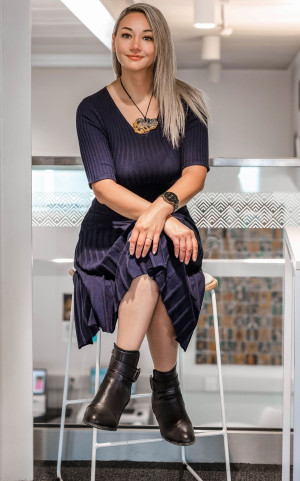 Mel Ahnau, Managing Director of Conscious Buying. Mel is sitting on a chair and looking towards the photographer.