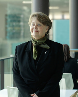 Karen English at MBIE’s office in Stout Street Wellington after winning Te Tohu Ratonga Tūmatanui – The New Zealand Public Service Medal. She is wearing a black outfit with a green scarf, She had a silver fern broach.