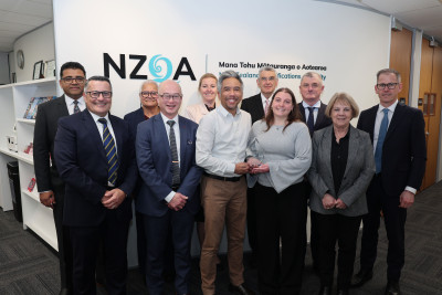 A group of people standing together in an office in front of NZQA (New Zealand Qualifications Authority) signage.