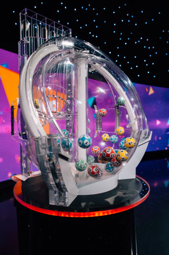 A close up of one of the six Lotto Machines in action. A variety of different coloured balls with different numbers are tossed around in a big clear ball sourced from an overseas supplier.