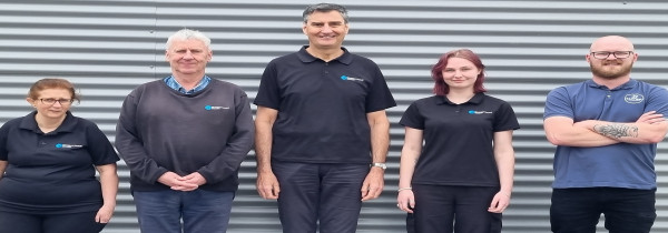 A team of five people stand together dressed in a dark blue uniform.