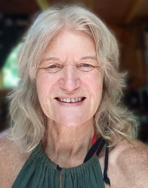 It’s a portrait photo of Kaye showing her head and shoulders. She has blonde hair and is wearing a green top. She is looking directly at the camera.