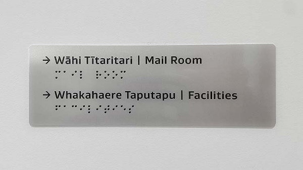 A sign showing Te Reo, English, then Braille all in the same place. 