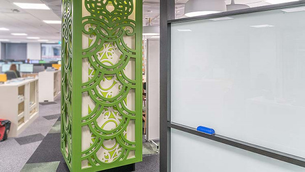 An example of culturally appropriate design, showcasing green Māori patterns wrapped around a rectangular column.